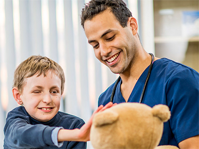 A Doctor and young boy playing with a teddy bear
